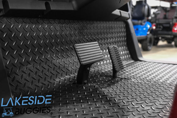 Black diamond-patterned floor mat with pedals.