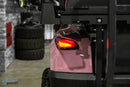 Pink golf cart with illuminated taillight.