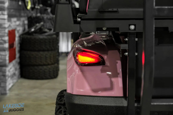 Pink golf cart with illuminated taillight.