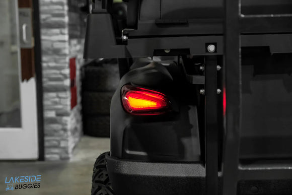Black golf cart with illuminated taillight.