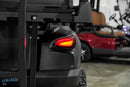 Black golf cart with illuminated taillight.
