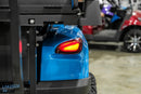 Blue golf cart with illuminated taillight.